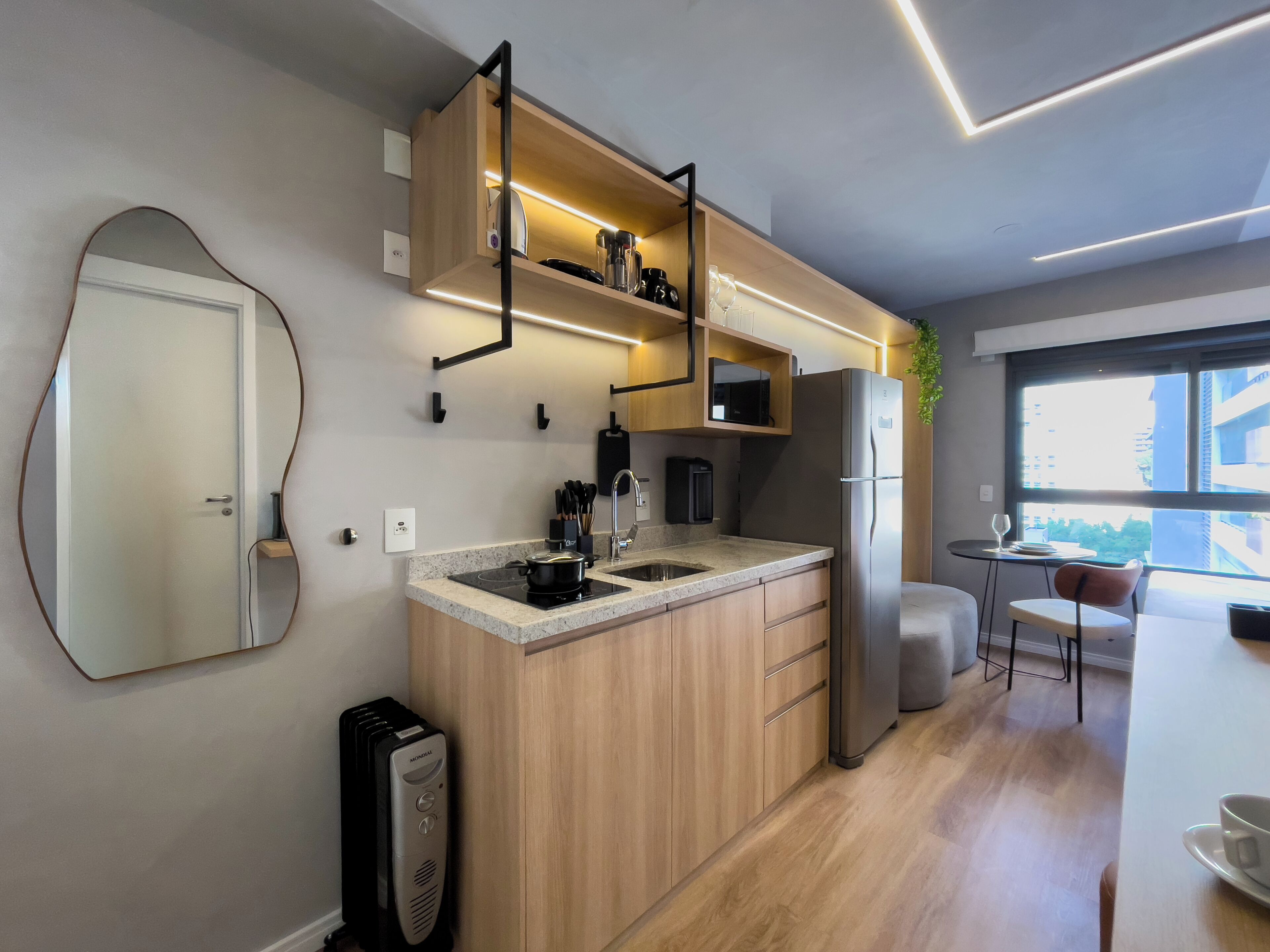 Una cocina moderna con armarios de madera, microondas integrado y refrigerador de acero inoxidable.