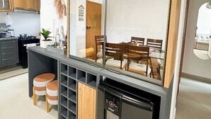A modern kitchen with a built-in refrigerator, wooden cabinets, and a dining area visible through a glass partition. - Apartment on the sand in the South beaches (Ilheus)
