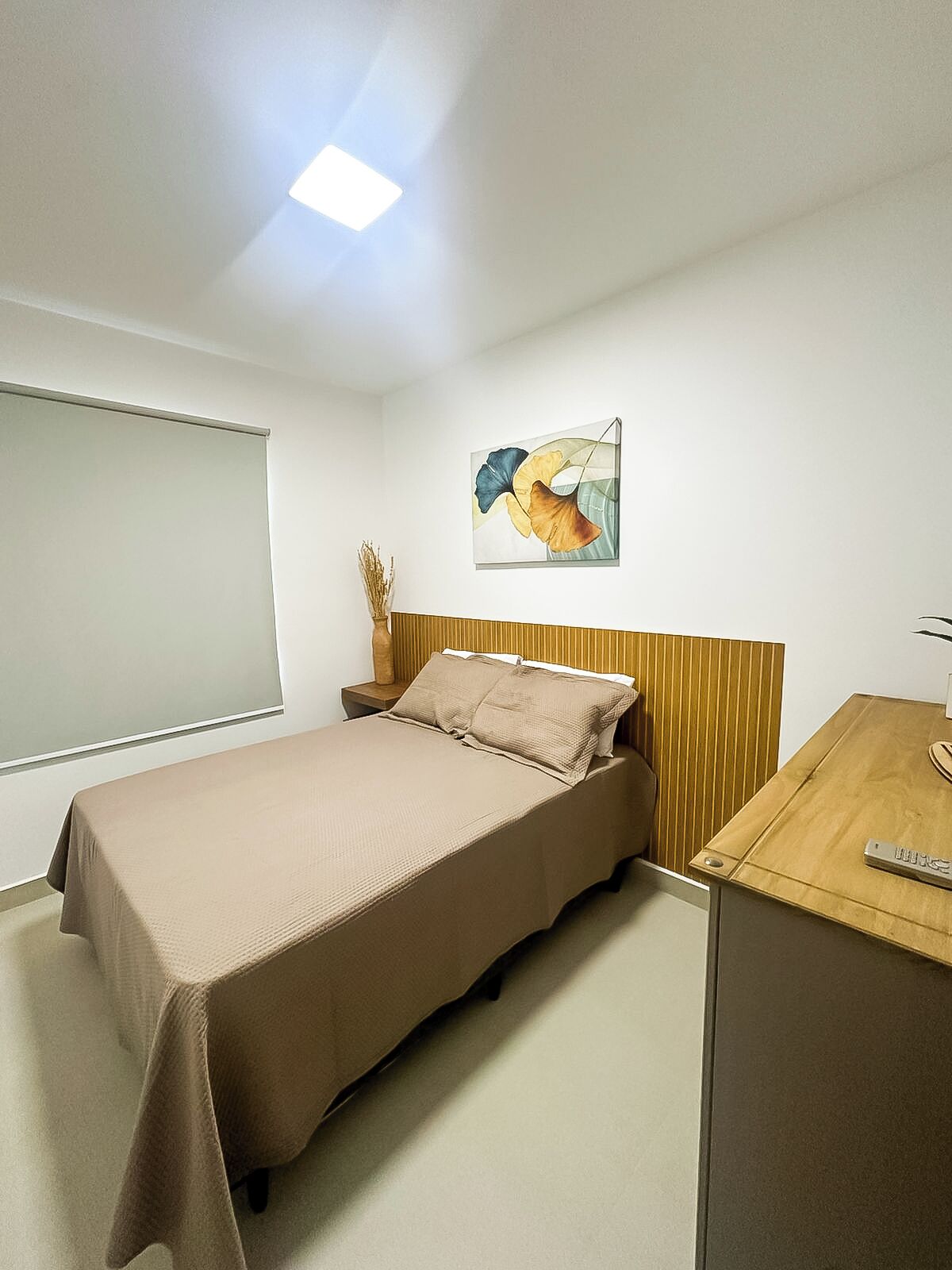 Habitació d'hotel amb llit, taulell de nit i un quadre a la paret.
