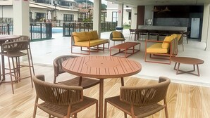 Un espace extérieur aménagé avec une terrasse, une table ronde et des chaises, des canapés et un coin bar.