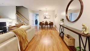 A modern living room with a sofa, a coffee table, and a fireplace. There is a dining area with a table and chairs.