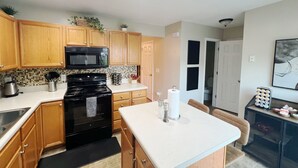 A modern kitchen with wooden cabinets, a black stove, and a white countertop.