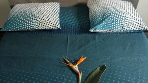 A bed with a teal bedspread and white pillows with a polka dot pattern.