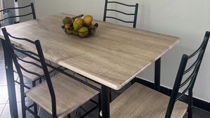 A dining area with a wooden table and black chairs. A fruit basket is on the table.