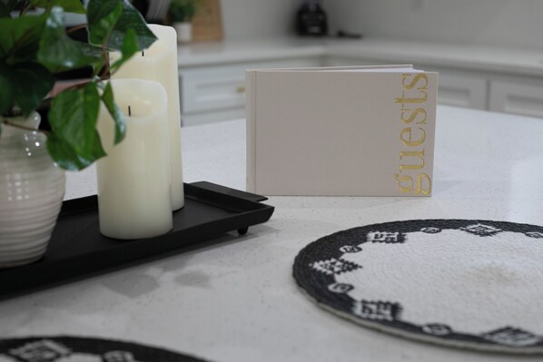 A table with a white tablecloth, a black tray, a white candle, and a card with the word "guests" on it.