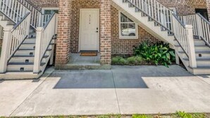 A two-story brick building with a central entrance, a small balcony, and a staircase leading to the upper floor. - Rose House - 2 Primary Suites, Easy Parking (Savannah)