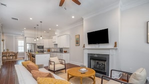 A spacious living room with a fireplace, a dining area, and a kitchen. - Rose House - 2 Primary Suites, Easy Parking (Savannah)