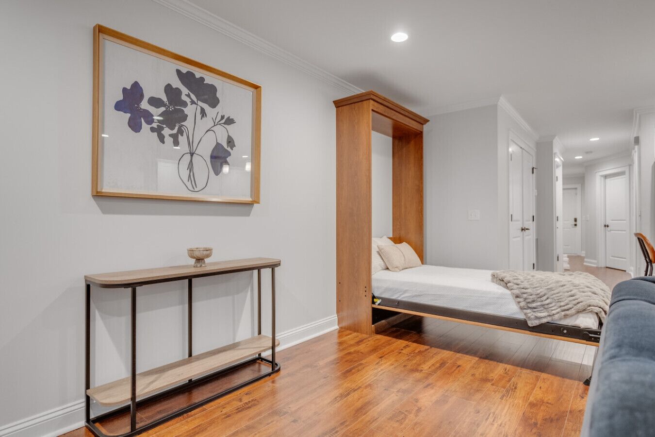 A bedroom with a bed, a console table, and a framed artwork on the wall.