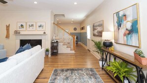 Un salon spacieux doté d’une cheminée, d’un escalier et d’un couloir menant à une autre pièce.