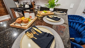Une cuisine moderne avec des comptoirs en granit, des armoires en bois et une chaise bleue.
