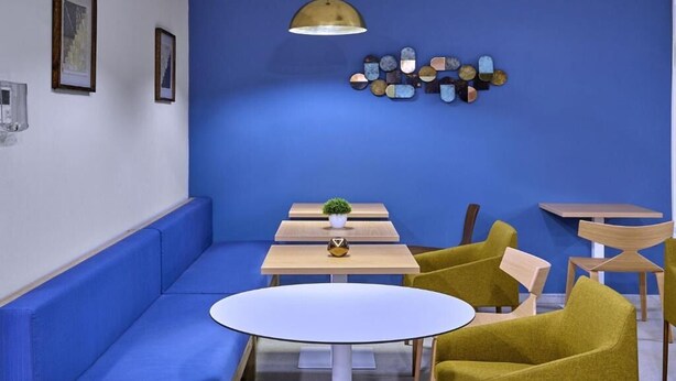 A modern lounge area with a blue sofa, a round table, and two yellow chairs. - Relaxing Stay Near CUN | 2 Rooms w/ Kitchenette, Pool, Rooftop Terrace & Shuttle (Moon Palace)