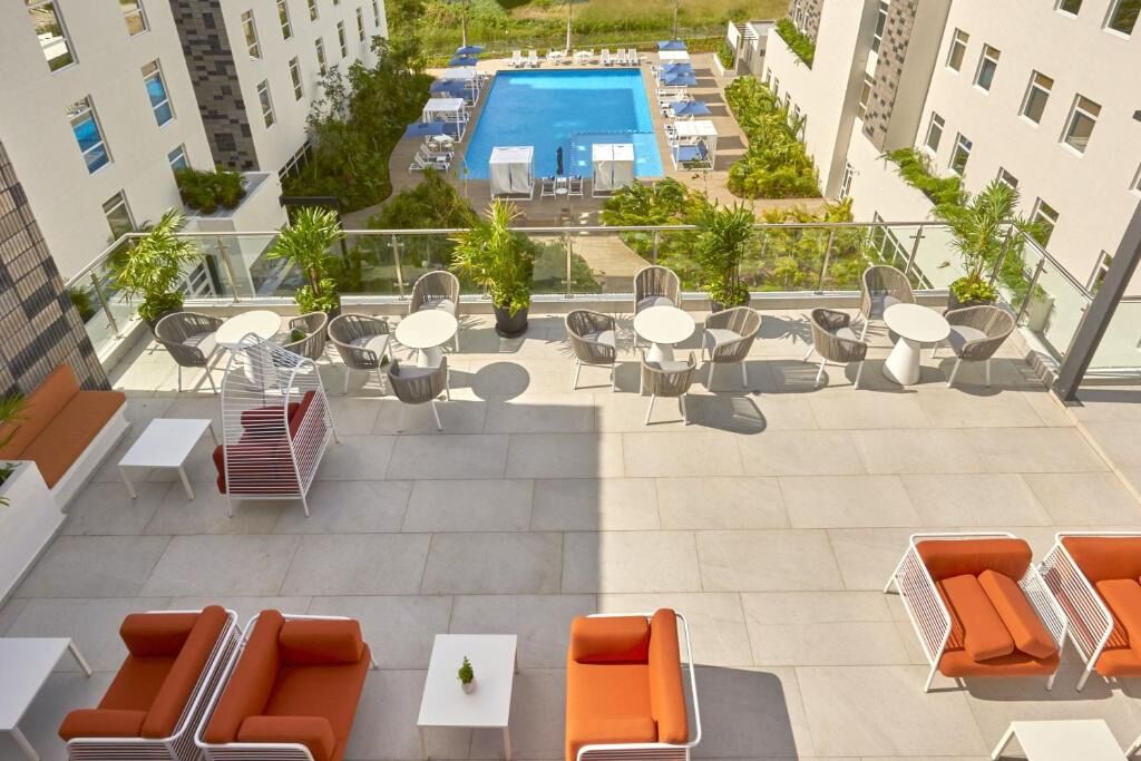A rooftop terrace with outdoor seating, a pool, and a view of surrounding buildings.