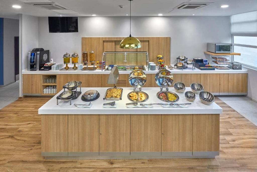 A buffet area with various food stations, a coffee machine, and a television on the wall.