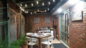 Een gezellig buiten eetgedeelte met een bakstenen muur, een barbecue en sfeerverlichting.