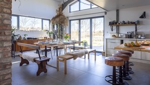 A spacious kitchen with wooden benches, a hanging light fixture, and a view of the outdoors.