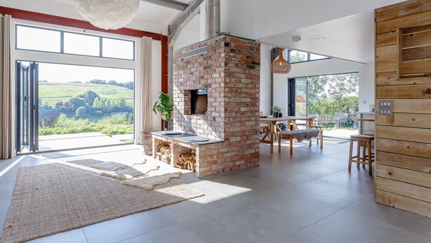 A spacious living area with a brick fireplace, large windows, and a view of the countryside.