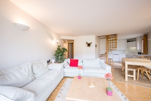 Un salon moderne avec un canapé, une table basse et un coin cuisine à l’arrière-plan.