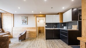 Una cocina moderna con suelo de madera, un comedor con un banco de madera y una pequeña mesa.