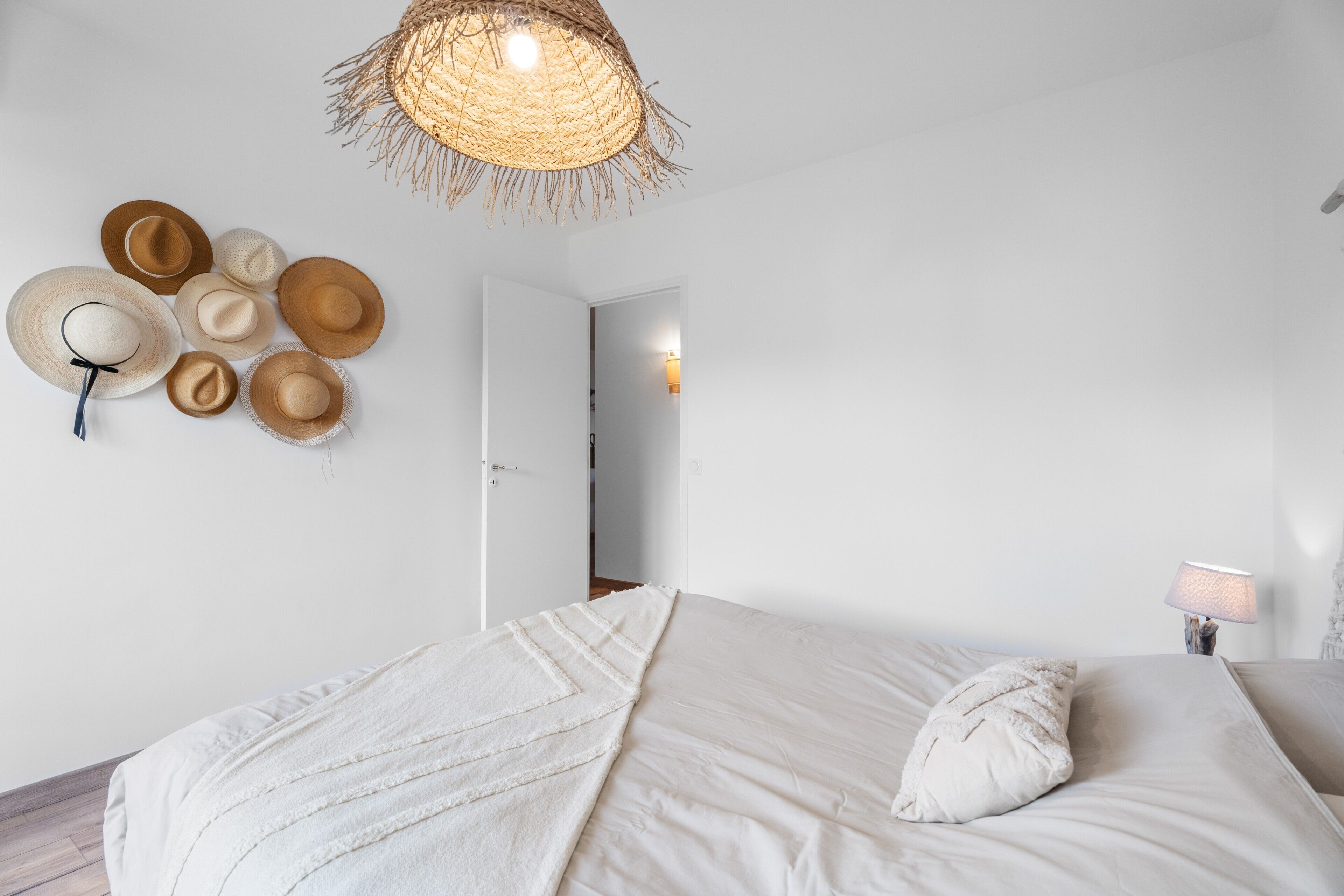 A bedroom with a bed, a hanging light fixture, and a wall with hats.