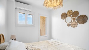 Une chambre à coucher avec un lit, une fenêtre, un climatiseur, une lampe et un élément décoratif mural.