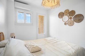 Une chambre à coucher avec un lit, une fenêtre, un climatiseur, une lampe et un élément décoratif mural.