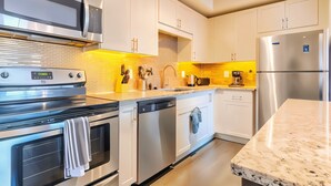 A modern kitchen with stainless steel appliances, white cabinetry, and a yellow backsplash. - Boulevard Stays Spacious 1BR King Suite Pool, Gym Access & Free Parking (Irving)