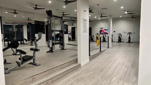 A gym with various exercise equipment, wooden flooring, and ceiling fans. - Boulevard Stays Spacious 1BR King Suite Pool, Gym Access & Free Parking (Irving)