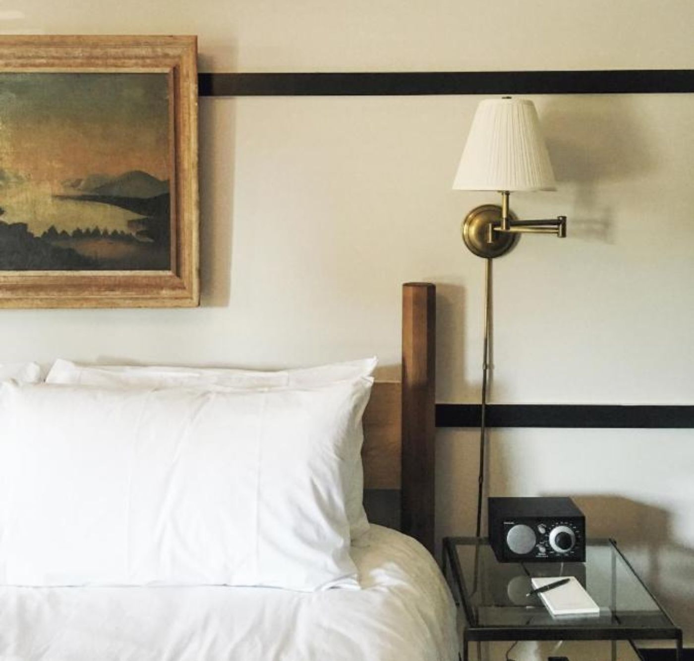 A hotel room with a bed, a nightstand with a lamp, and a painting on the wall.