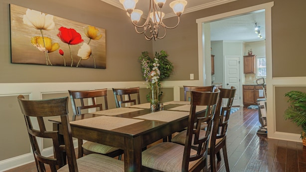 A dining area with a wooden table and chairs, a chandelier, and a floral painting on the wall. - Serene Family Hideaway 4Br w Pool Table (Fortson)