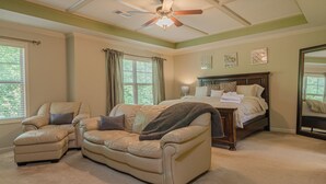A bedroom with a bed, two sofas, a ceiling fan, and large windows. - Serene Family Hideaway 4Br w Pool Table (Fortson)