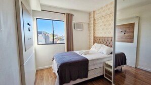 Une chambre moderne avec un lit, une fenêtre avec des rideaux, un climatiseur fixé au mur et une tête de lit en bois.