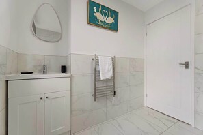 Een badkamer met een wit wastafelmeubel, een handdoekhouder, een spiegel en een deur.