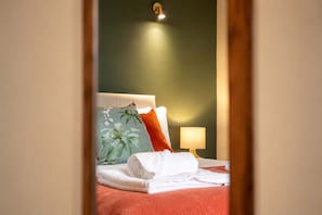 A hotel room with a bed, pillows, a lamp, and a folded towel.