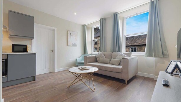 A modern living room with a sofa, a coffee table, a TV, and a window with curtains.