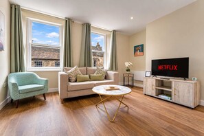 Een woonkamer met een bank, een salontafel, een televisie en een kast.
