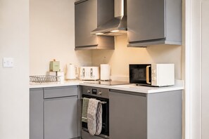A modern kitchen with grey cabinets, a microwave, a toaster, and a kettle.