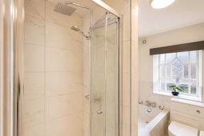 A modern bathroom with a glass-enclosed shower, a window with a view, and a sink with a mirror.