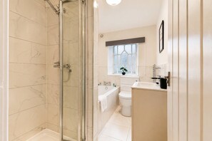 A bathroom with a glass-enclosed shower, a bathtub, a toilet, and a sink.