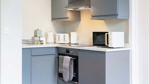 A modern kitchen with grey cabinets, a microwave, a toaster, and a kettle.