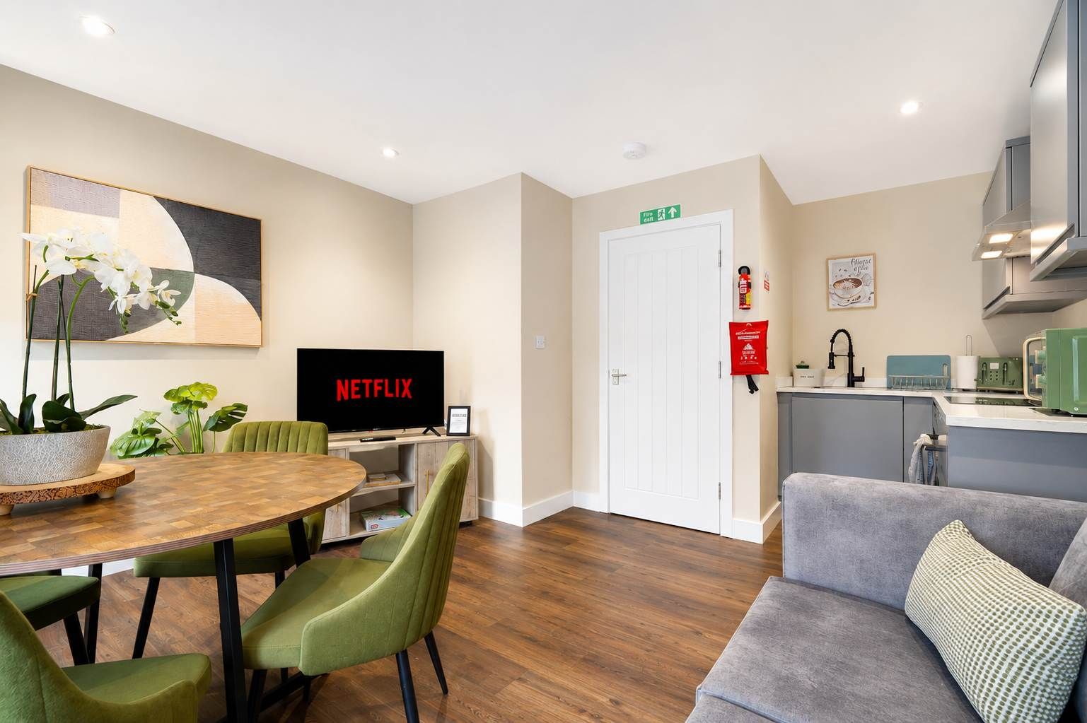 Un salon moderne comprenant un coin repas, un téléviseur à écran plat diffusant du contenu de « NETFLIX », un coin cuisine et un canapé.