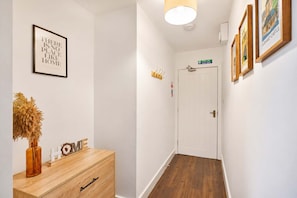 A hallway with a wooden dresser, a framed quote on the wall, and a door at the end. - Modern 2BR | Central Barnard Castle | Sleeps 3 (County Durham)