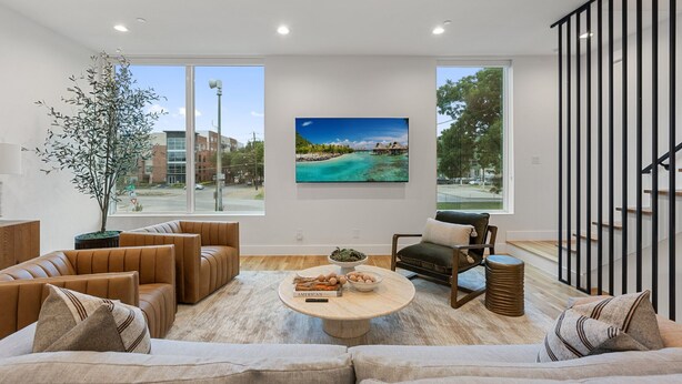 Un moderno salón con un gran ventanal, un cuadro de playa y una planta en maceta.