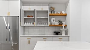 Una cocina moderna con armarios blancos, un refrigerador de acero inoxidable y una encimera de mármol.