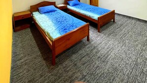 A room with two wooden beds, a ceiling fan, and a door. - Serene – A Stylish Vacation Home with Breathtaking Views (Gilgit Baltistan)