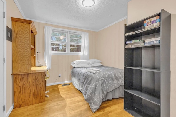Un dormitorio con una cama, un armario de madera, una ventana y una estantería.