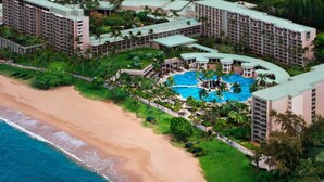 Ein Resort mit mehreren Gebäuden, einem großen Poolbereich und einem Strand.