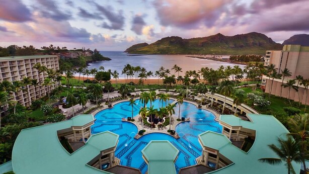 Ein Resort mit mehreren Swimmingpools, Palmen und Blick auf den Strand.