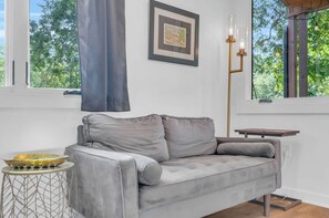 Un salon moderne avec un canapé gris, un tableau encadré et une lampe sur pied.