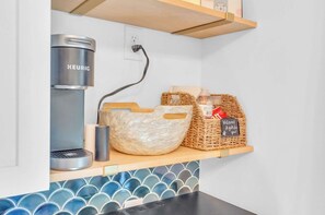 Une petite cuisine équipée d’une machine à café Keurig, d’un panier en osier et d’un autre panier en rotin avec une étiquette.