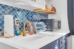 Una cocina con cubierta blanca, un tostador, un microondas y un lavamanos.